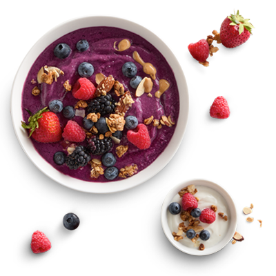 A delicious berry smoothie bowl on a marble countertop. The smoothie bowl contains strawberries, blueberries, blackberries, peanut butter, and granola.