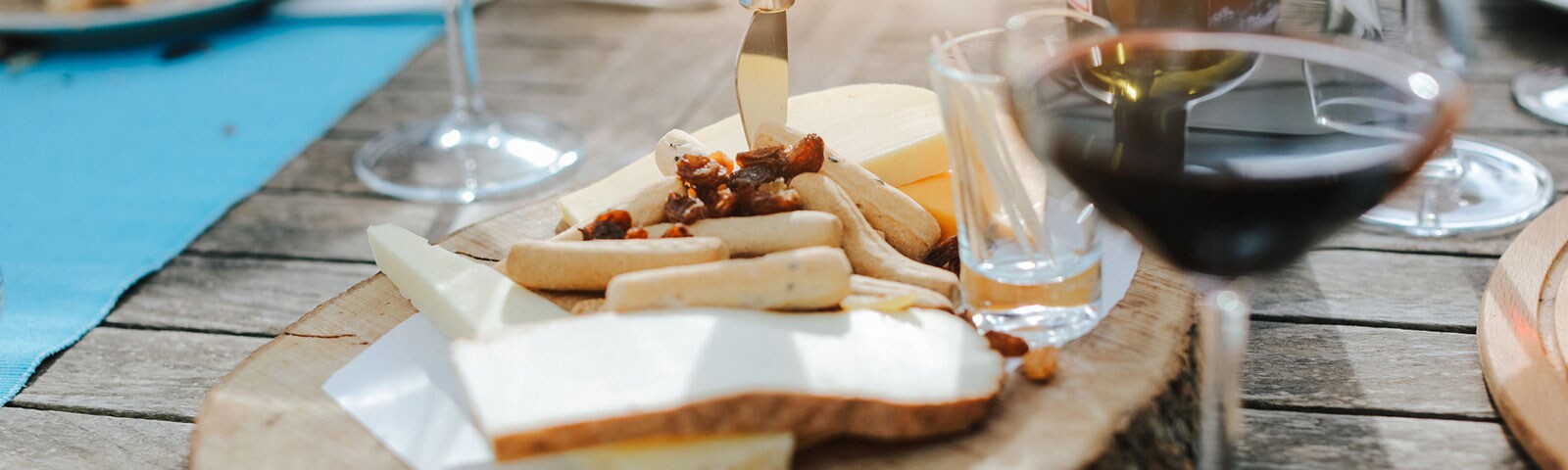Wine and snacks served on a wooden tray on a wooden table