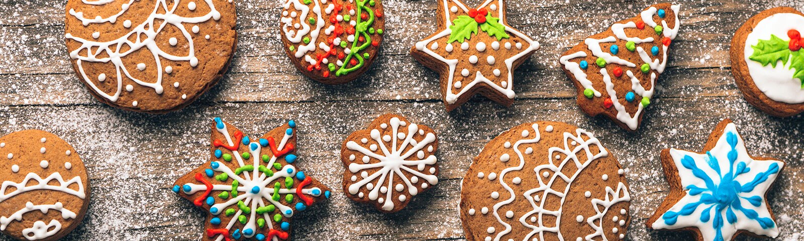 decorative holiday cookies on a rustic wooden table sprinkled with powdered sugar