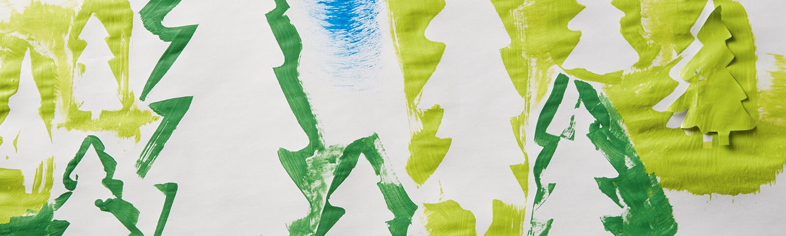 A long, horizontal piece of white paper covered in tree silhouettes of various sizes and shades of green A long, horizontal piece of white paper covered in tree silhouettes of various sizes and shades of green